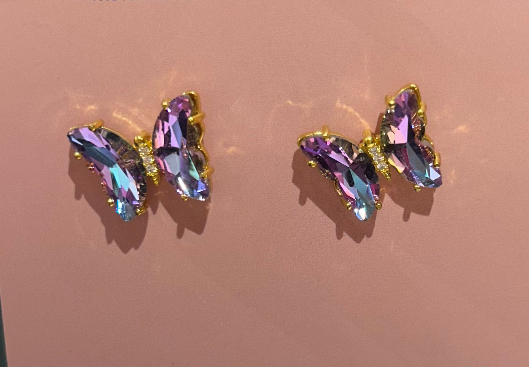 Pair of earrings with multicolored gemstones on a pink background
